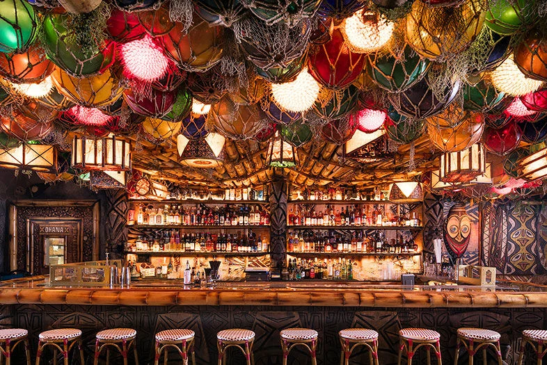 Inside False Idol—tile, carved-tiki posts, low-ceilinged bar