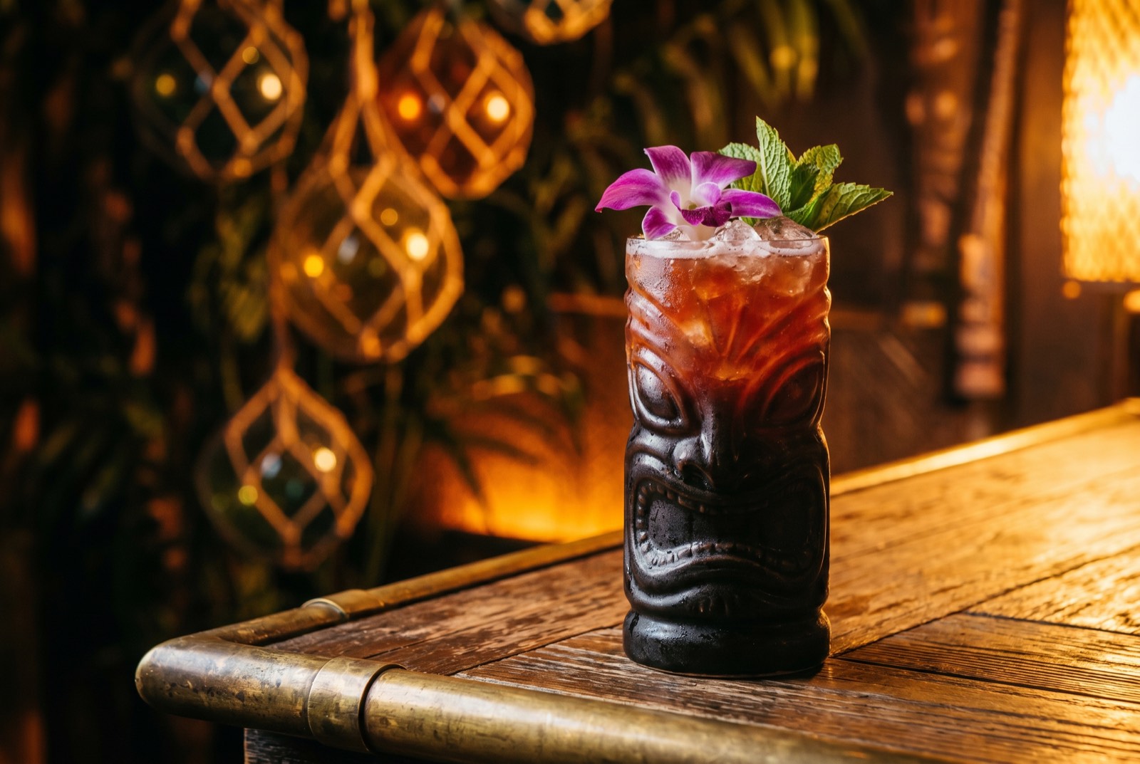 A’a’po’e cocktail in a carved dark ceramic tiki mug, deep reddish-amber with an orchid and mint garnish, lit by warm tungsten light in the dim Forbidden Altar bar