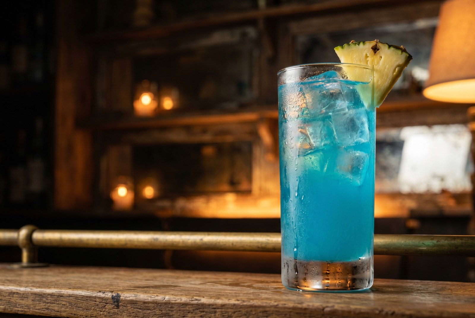 Blue Hawaii cocktail, vivid tropical blue in a tall highball glass over ice with a pineapple wedge, against the dark Forbidden Altar bar